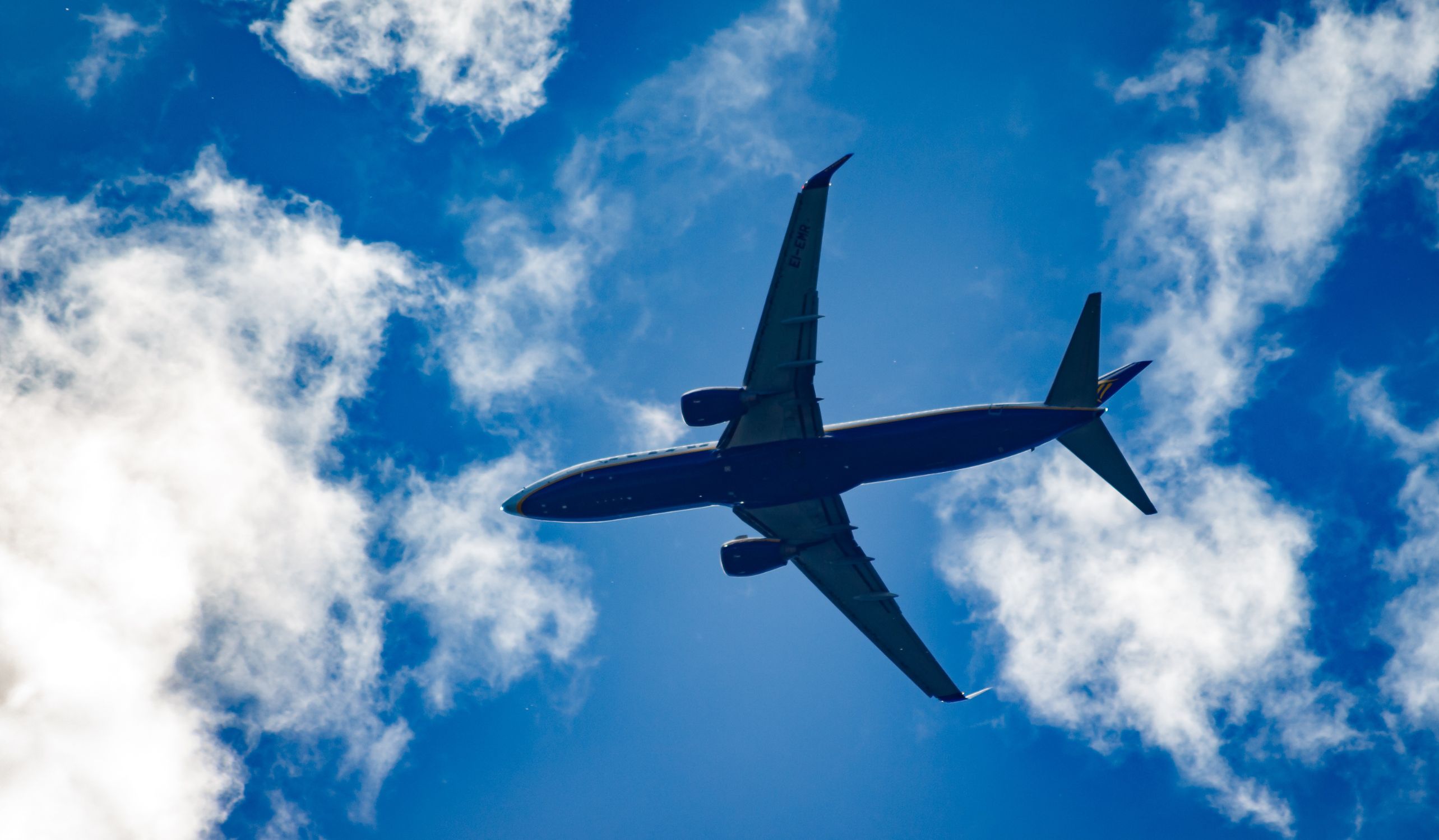 Airplane flying in a bright blue sky with clouds